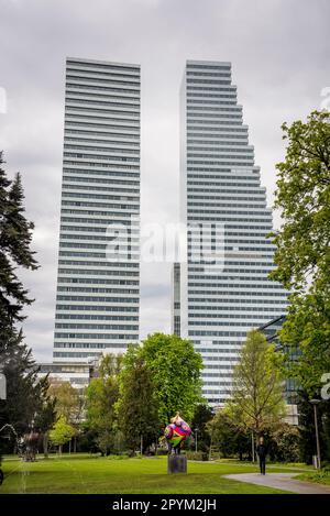 Statua Nana di Niki de Saint Phalle nel giardino del Museo Tinguely, e Roche Towers Building 1 e Building 2 grattacieli progettati da Architecture f Foto Stock