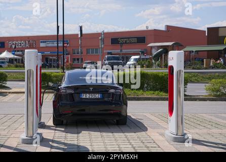 Mondovi, Italia - 18 aprile 2023: Un colpo statico di una carica a doppio motore Tesla Model 3 nera al Mondovi Supercharger in una soleggiata giornata primaverile. S Foto Stock