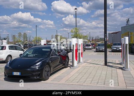 Mondovi, Italia - 18 aprile 2023: Un colpo statico di una carica a doppio motore Tesla Model 3 nera al Mondovi Supercharger in una soleggiata giornata primaverile. S Foto Stock