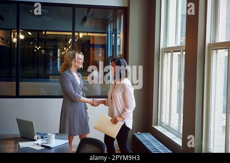 Benvenuto nel team. due donne d'affari sorridenti che scuotono le mani in un ufficio. Foto Stock