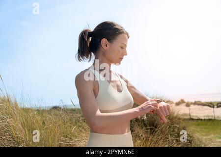 Indossate una donna sportiva che controlla il suo fitness tracker dell'orologio intelligente Foto Stock
