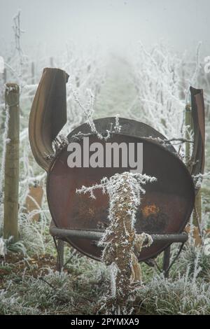 Gelo invernale nei vigneti durante la potatura. Barile di olio tipico usato in Borgogna per bruciare i tagli di legno della vite Foto Stock