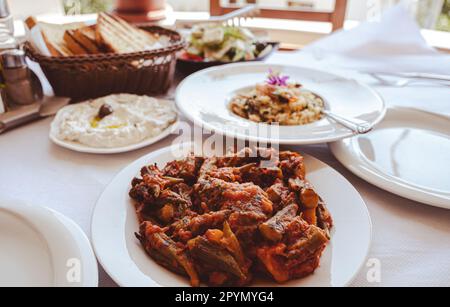 cibo tradizionale balcanico, okra al forno e verdure con tzatziki su piatti bianchi Foto Stock
