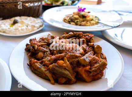 cibo tradizionale balcanico, okra al forno e verdure con tzatziki su piatti bianchi Foto Stock