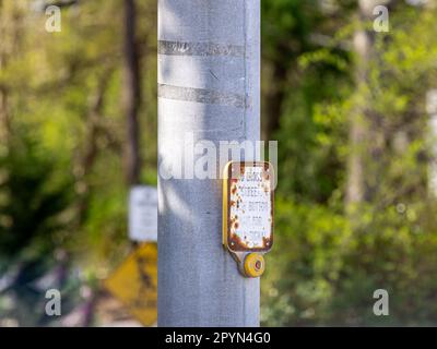 Immagine dettagliata di un vecchio cartello e pulsante che attiva i semafori in modo che qualcuno possa attraversare la strada Foto Stock