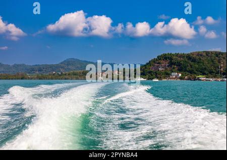 Onde da un motoscafo sul mare blu con spruzzi e un sentiero da una barca o yacht. Il concetto di viaggio e viaggio durante la vacanza in caldo asiatico Foto Stock