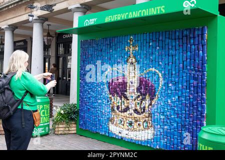 Londra, Regno Unito. 4th maggio, 2023. Il bunting di Union Jack rende il mercato di Covent Garden ancora più fotogenico per i turisti in vista dell'incoronazione di Re Carlo III sabato 6 maggio. Qui una parete di lattine è stata verniciata a spruzzo con un'immagine gigante della corona di Sant'Edoardo che viene indossata solo per le incoronazioni. Credit: Anna Watson/Alamy Live News Foto Stock