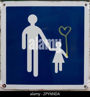 Parigi, Francia - 05 01 2023: Un cartello stradale blu e bianco con un padre e una figlia che tengono le mani e un cuore giallo disegnato Foto Stock