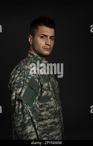 soldato depresso in uniforme che soffre di ptsd isolato su nero, immagine stock Foto Stock