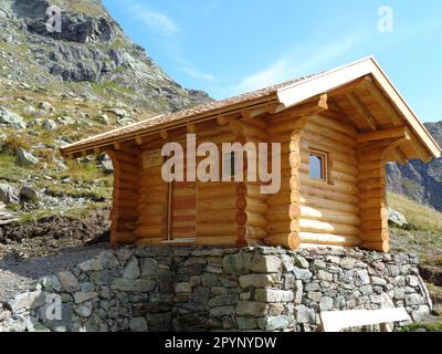 Kleine Almhütte/Schutzhütte aus Holz inmitten einer malerischen Bergszene Foto Stock