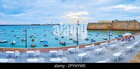 CADICE, SPAGNA - 21 SETTEMBRE 2019: Panorama della passeggiata la Caleta con pranzo all'aperto, molte barche ormeggiate e castelli medievali in background, il mese di settembre Foto Stock