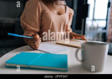 Primo piano ripresa ritagliata di irriconoscibile studente africano idee di brainstorming e la scrittura sul notebook di carta in auto educazione seduta a. Foto Stock