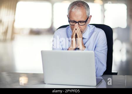 Lavora per abbassarlo. un uomo d'affari maturo che guarda stressato mentre lavora nel suo ufficio. Foto Stock