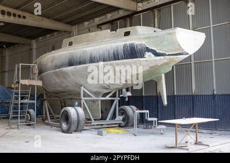 Lo yacht in vetroresina viene riparato in un cantiere. Restauro barche Foto Stock