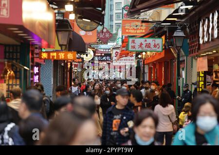 Una vivace strada dello shopping animata da gente e illuminata da una varietà di colorate insegne al neon in Cina Foto Stock