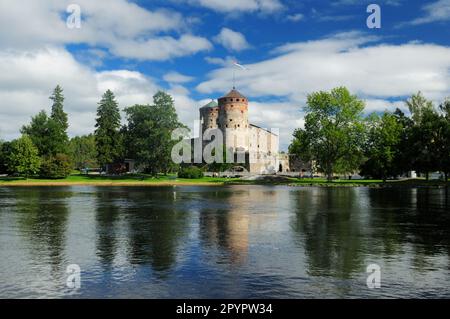 Il Castello di Olavinlinna si riflette nel lago di Savonlinna Finlandia in Una bella giornata estiva di sole con Alcune nuvole nel cielo blu Foto Stock