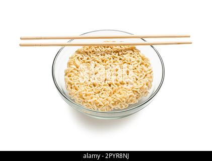 Spaghetti istantanei crudi in ciotola con bacchette di legno su fondo bianco Foto Stock