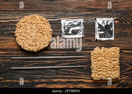 Spaghetti istantanei crudi con condimento su fondo in legno Foto Stock