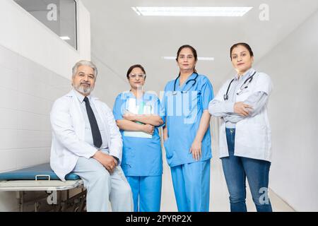 Team di medici indiani maschi e femmine fiduciosi personale infermieristico con stetoscopio in piedi a braccia incrociate in piedi in ospedale, concetto di assistenza sanitaria. Foto Stock