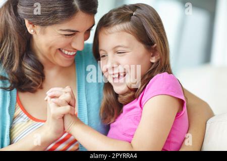 Tenere le mani affettuosamente. Una ragazza carina che tiene le mani con la madre e ridendo. Foto Stock