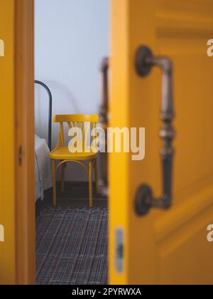 Bordo del letto e una sedia accanto in piedi dalla porta a mezza apertura, messa a fuoco selettiva. Concetto di cura del paziente a letto Foto Stock