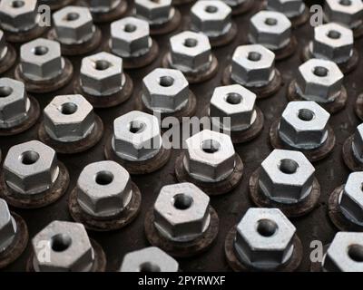 Bulloni esagonali in metallo in produzione, vista dall'alto e messa a fuoco selettiva. Fabbricazione di dispositivi di fissaggio, concetto industriale Foto Stock