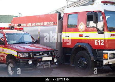 Vigili del fuoco, camion e servizi di soccorso in stazione pronti per l'estinzione, l'emergenza e il trasporto. Veicoli dei vigili del fuoco parcheggiati all'esterno per motivi di sicurezza Foto Stock