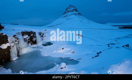 Cascata ghiacciata di fronte all'iconica montagna all'ora blu Foto Stock