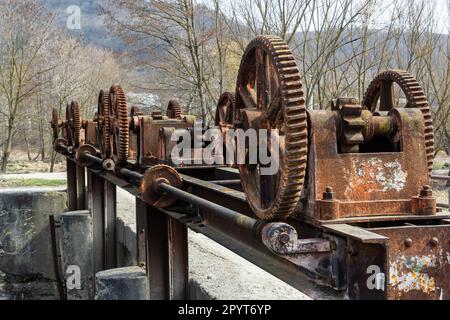 vecchio meccanismo meccanico di ingranaggi di metallo sulla diga abbandonata. Foto Stock