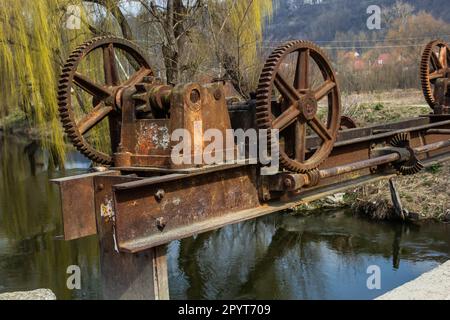 vecchio meccanismo meccanico di ingranaggi di metallo sulla diga abbandonata. Foto Stock