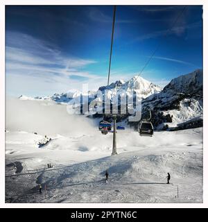 DALLA SERIE ADELBODEN funivia nella neve di fronte al paesaggio invernale a Adelboden, Oberland Bernese, Canton Berna, Svizzera. La pittoresca cittadina di Adelboden è un idillio svizzero nelle Alpi Bernesi, vette impressionanti, paesaggio invernale unico, popolare area sciistica, pascoli alpini, cascate frettolose, accoglienti case in legno. A causa del cambiamento climatico e di una quantità sempre minore di neve, il classico centro sportivo invernale si sta riorientando e la stagione estiva sta diventando sempre più importante. Foto scattata con iPhone, app Hipstamatic. Foto Stock