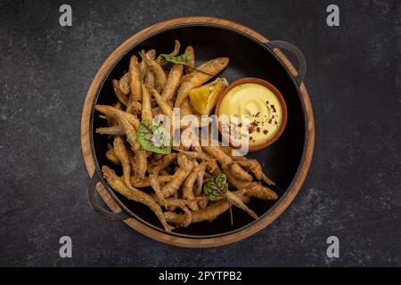 Acciughe fritte deliziosamente servite con una salsa piccante e limone Foto Stock