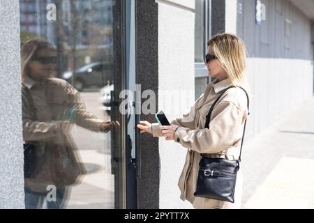 Immagine ritagliata della femmina che immette codice chiave segreto per ottenere l'accesso e passare edificio utilizzando l'applicazione sul telefono cellulare, donna premendo i pulsanti su Foto Stock