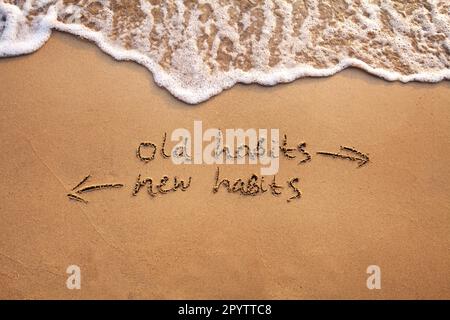vecchie abitudini vs nuove abitudini, concetto di cambiamento di vita scritto sulla sabbia Foto Stock