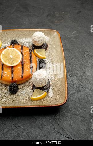vista frontale goloso dolce torta con fettine di limone e caramelle al cocco sul banco scuro torta dessert tè dolce torta caramella Foto Stock