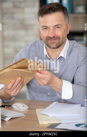 buon uomo d'affari che riceve le buste in ufficio Foto Stock