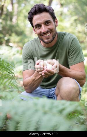 felice uomo che raccoglie funghi nella foresta Foto Stock
