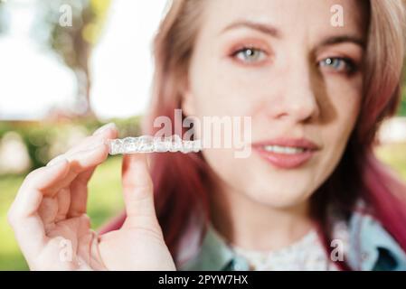 Dentale care.Smiling ragazza felice con bretelle sui suoi denti tiene allineatori nelle sue mani e mostra la differenza tra loro Foto Stock