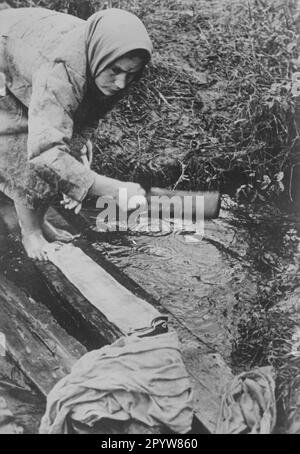 Una donna russa lava i vestiti nel villaggio dei soldati a Kujasche sul fronte orientale. Foto: Götze. [traduzione automatica] Foto Stock