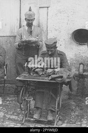 Un soldato con una macchina da cucire che mendia una divisa. Secondo il numero riportato sulle epaulette, i soldati appartengono alla riserva Grenadier Regiment 100. [traduzione automatica] Foto Stock