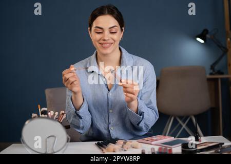 Beauty blogger giovane donna caucasica sta trasmettendo e registrando la trasmissione su uno smartphone. tiene il rossetto nelle sue mani fa una revisione di Foto Stock