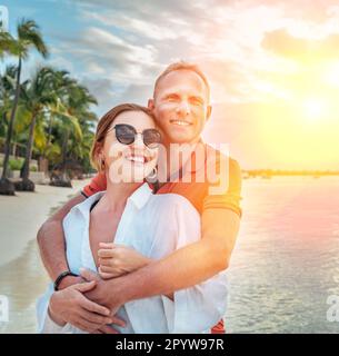 Coppia innamorata che abbraccia la spiaggia sabbiosa esotica mentre fanno una passeggiata serale sul mare di Trou-aux-Biches sull'isola di Mauritius. Persone relationsh Foto Stock