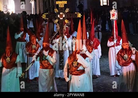 Cofradias indossando cappe a forma di cono rosso durante la processione silenziosa di mezzanotte che segna il Venerdì Santo alla settimana Santa o Semana Santa, 6 aprile 2023 a Ronda, Spagna. Ronda, insediata per la prima volta nel 6th° secolo a.C., ha tenuto le processioni della settimana Santa per oltre 500 anni. Foto Stock