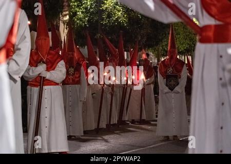 Cofradias con cappe a forma di cono rosso camminano per le strade durante la processione silenziosa di mezzanotte che segna il Venerdì Santo alla settimana Santa o Semana Santa, 6 aprile 2023 a Ronda, Spagna. Ronda, insediata per la prima volta nel 6th° secolo a.C., ha tenuto le processioni della settimana Santa per oltre 500 anni. Foto Stock