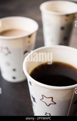 Un primo piano di due tazze da caffè in ceramica seduti su un tavolo nero con un motivo a stella Foto Stock