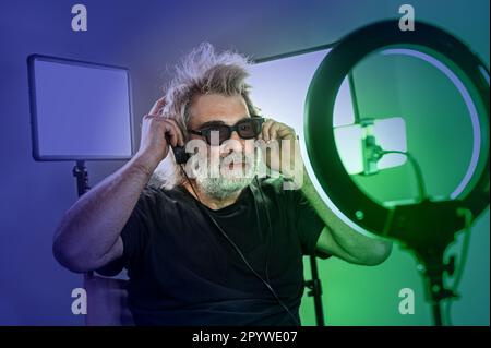 Radio host, affascinante influencer, registra uno spettacolo dal vivo con materiale e attrezzature per la fotocamera. Foto Stock