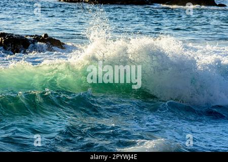 Piccola onda di rottura con acqua nebulizzata rilasciato nell'aria nel mare di Salvador, Bahia, Brasile Foto Stock