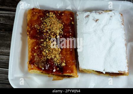 Torta di mele farcita con mela cremosa, cannella e sciroppo di miele dolce zuccherato e sormontata con pistacchi, noci e zucchero a velo, delizioso dolcificato al forno Foto Stock