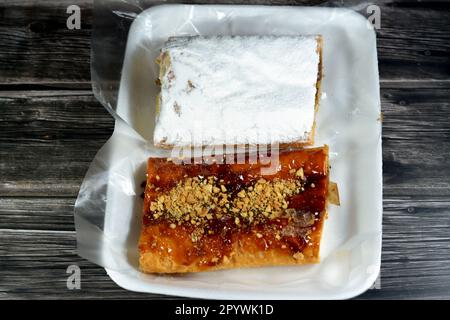 Torta di mele farcita con mela cremosa, cannella e sciroppo di miele dolce zuccherato e sormontata con pistacchi, noci e zucchero a velo, delizioso dolcificato al forno Foto Stock