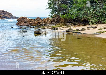 Acque di un piccolo fiume che si dirige verso il mare tra la sabbia e la foresta pluviale a Trindade, sulla costa meridionale dello stato di Rio de Janeiro Foto Stock